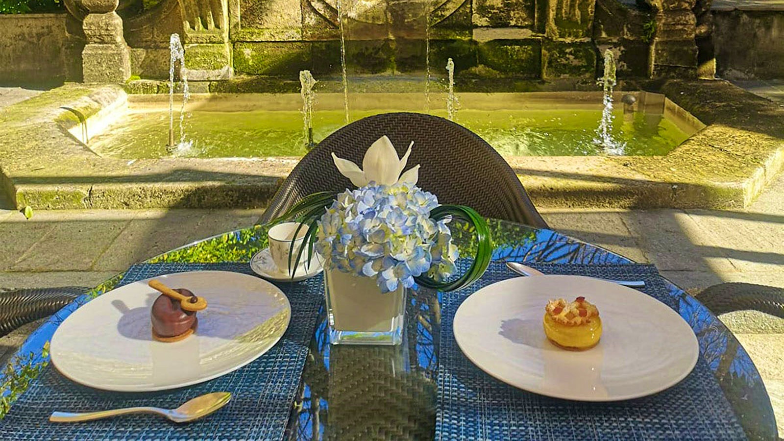 A table outside at Acanto, set with two desserts, near a water fountain